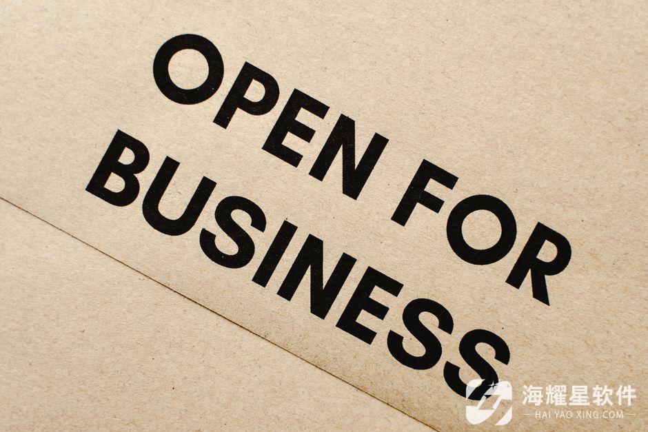 Close-up of an 'Open for Business' sign on a textured brown paper background.